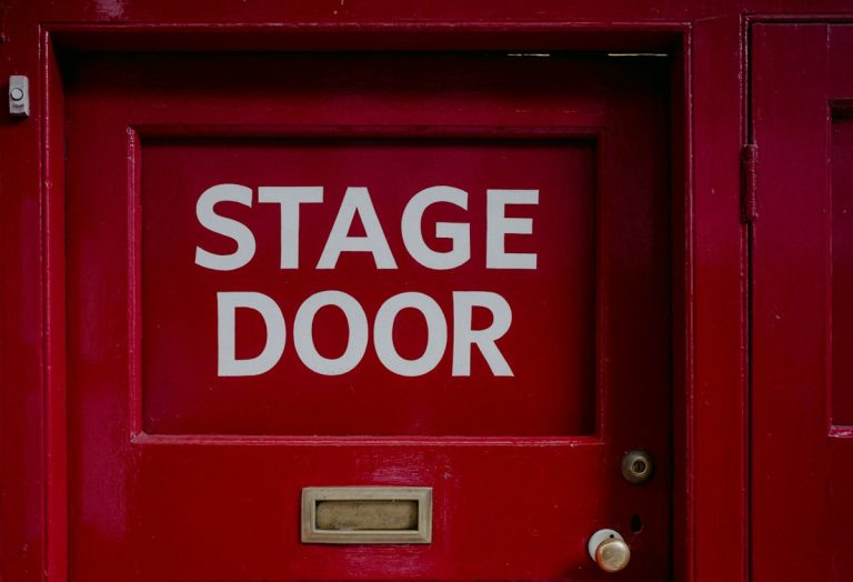 A red door with a sign that says stage door