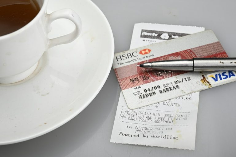 Credit card, pen, and receipt beside a coffee cup