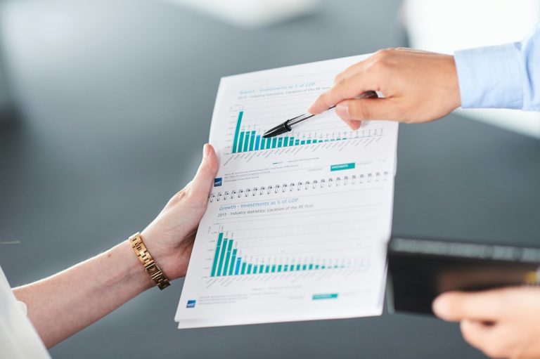 Two people analysing a document with green bar charts