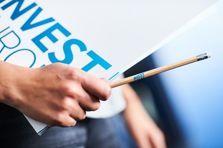 Hand holding invest sign and pencil